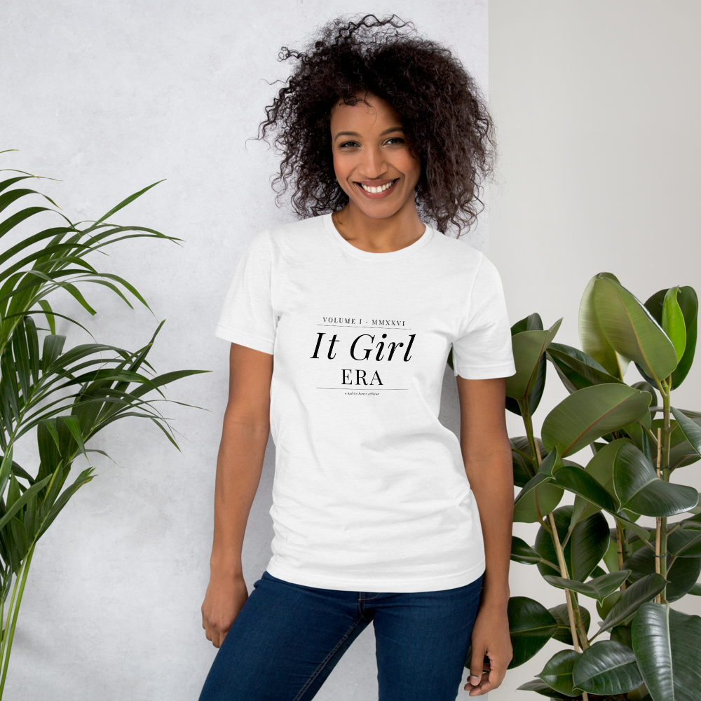 IT GIRL ERA Tee on female model, curly hair, lifestyle setting with plants